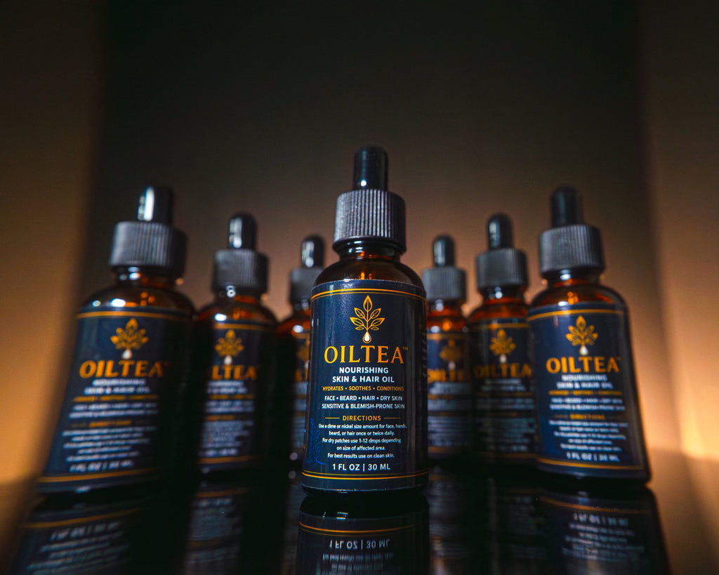 Cluster of OILTEA bottles in warm light, with one bottle in front