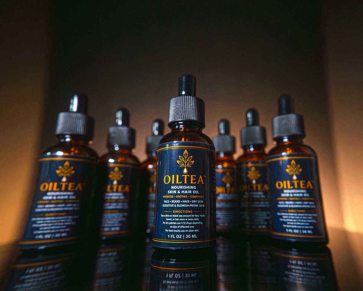 Cluster of OILTEA bottles in warm light, with one bottle in front