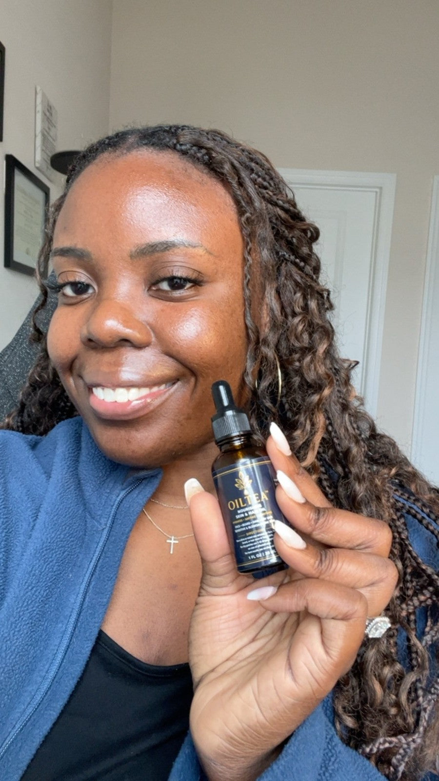 Smiling customer holding up a bottle of OILTEA Nourishing Skin and Hair Oil