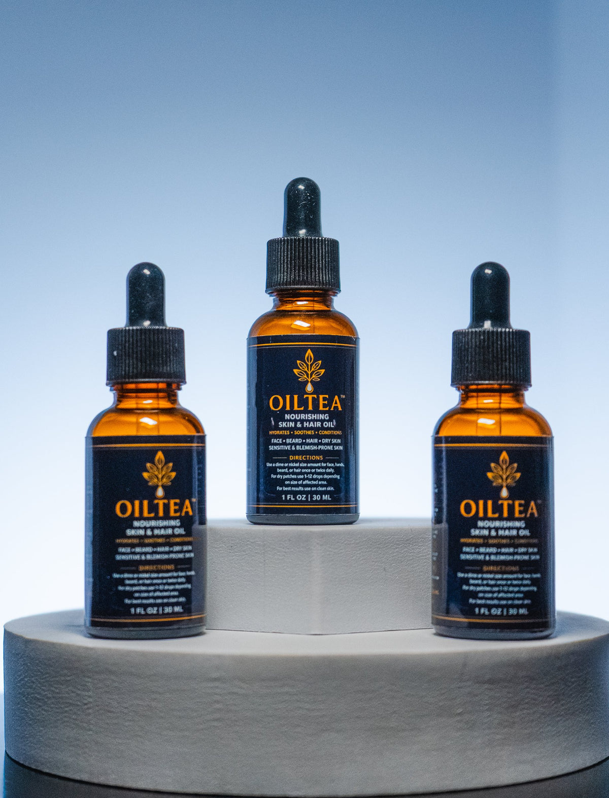 Three OILTEA bottles on a stone pedestal